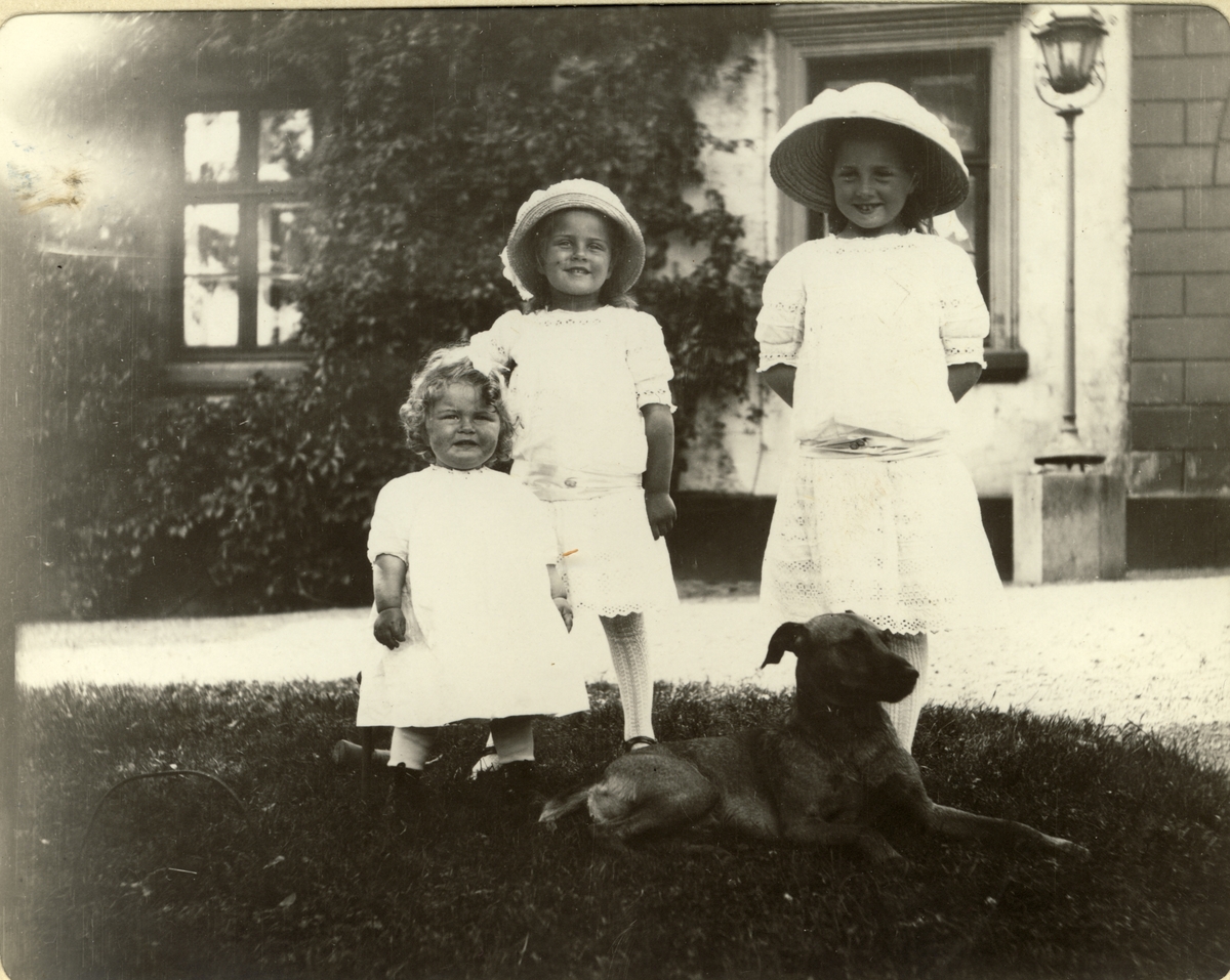 Søstrene Karen, Lucy og Mimi Egeberg med hunden "Bob" i parken på Bogstad gård i Oslo. Fotografert 1912.