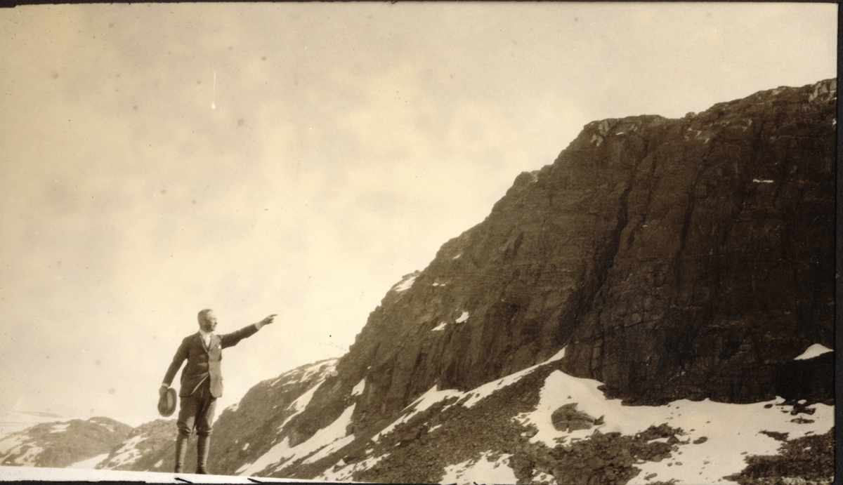 Westye Parr Egeberg peker på  en fjellside på ukjent sted. Fotografert 1923.