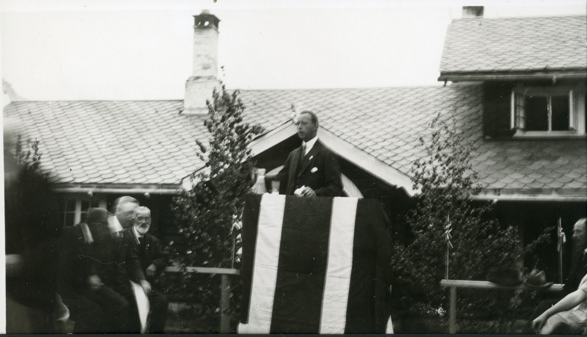 Einar W. Egeberg jr holder tale på en improvisert talerstol under en folkefest på jaktslottet Malungen 22. Juni 1924. Til venstre skimtes antagelig faren, Einar Westye Egeberg sr.