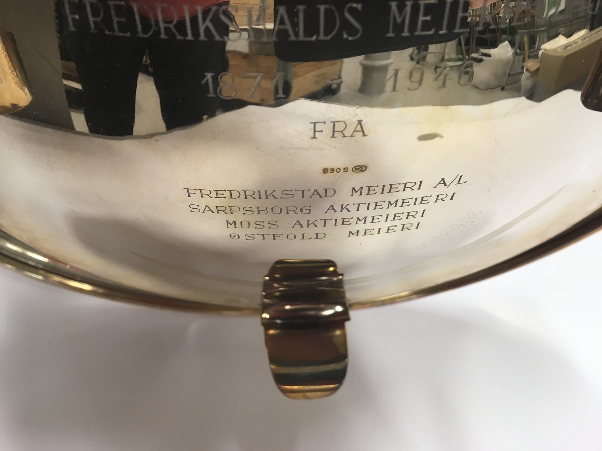 Sølvfat på tre ben, gitt til Fredrikshald meieribolag 1947 fra Østfold meierier. Gravert hilsen