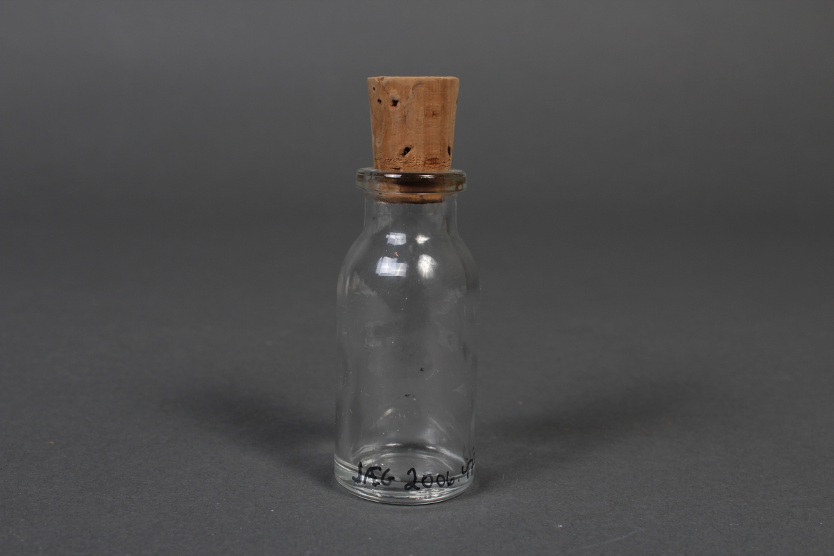 Liten flaske i klart glass, med kork.
Gjenstanden har vore brukt i samband med dyrlegearbeid på Jæren.