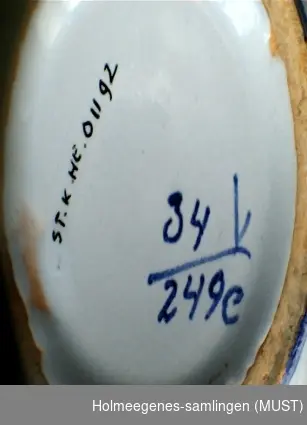 Smal mindre vase i trompettform. Laget av keramikk med tykk glasur i blått og sort på utsiden, sort på innsiden. Produsert ved Gwenni Pottery, sannsynlig engelsk.
