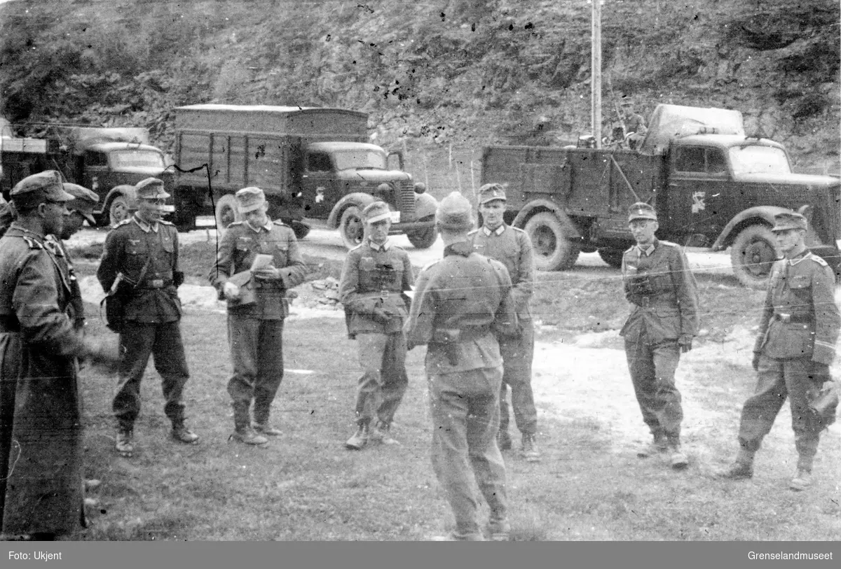 En gruppe soldater står i samtale foran en rekke med lastebiler merket med reinsdyr på dørene. 2. Gebirgs Division? 