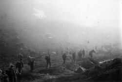 Soldater på marsj med hest i et fjellandskap i tåke.