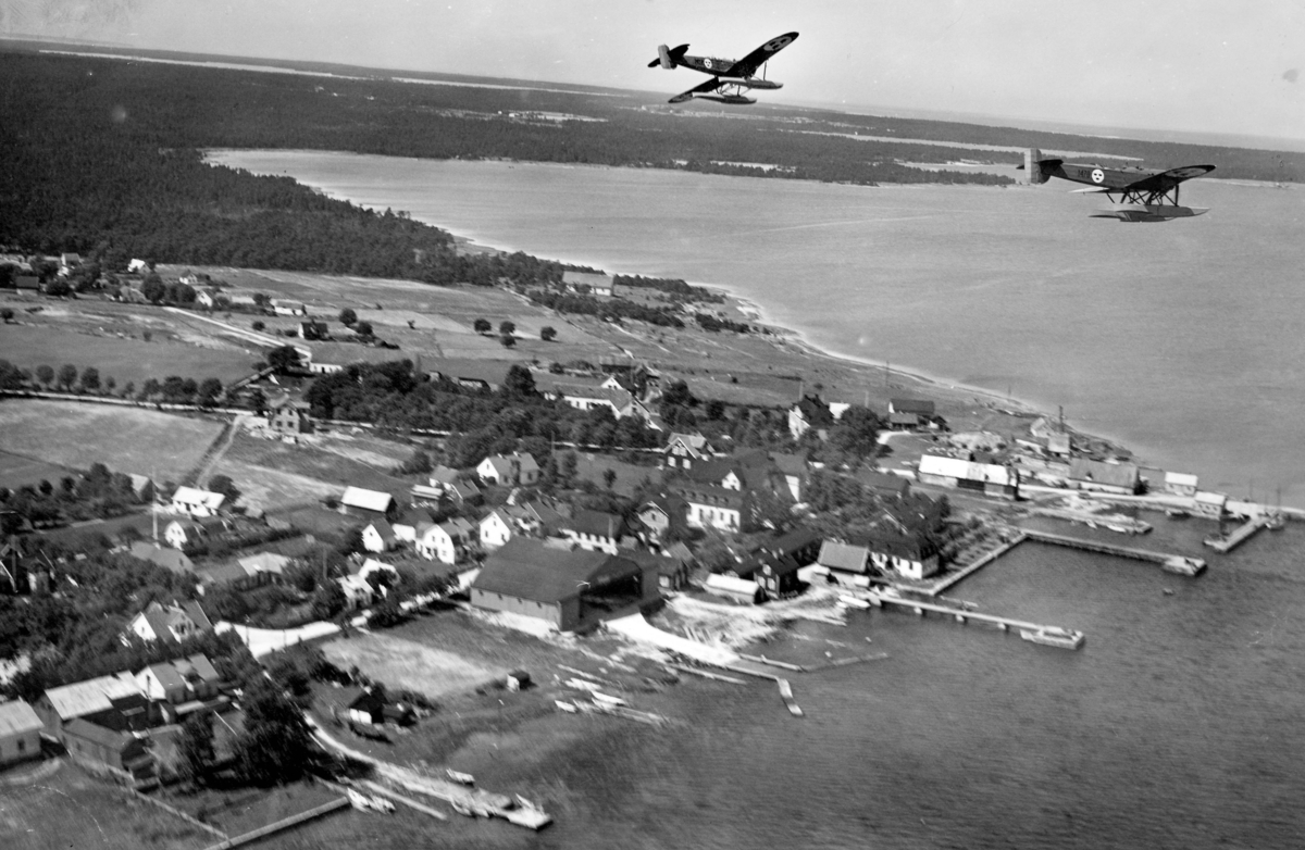 Flygbild av två flygplan S 5, Heinkel He 5 Hansa över kust. Flygplan 2452 och 1470. Eventuellt är platsen Fårösund. 1930-tal.