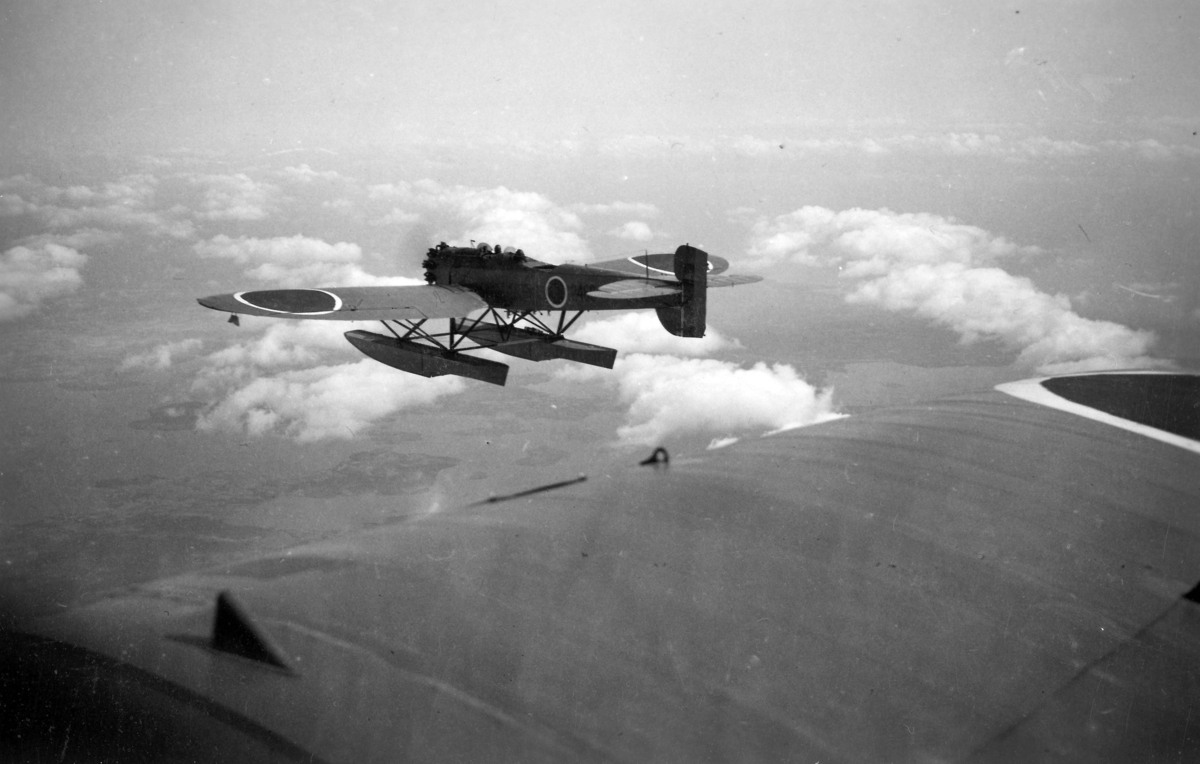 Flygbild av flygplan S 5A under övning juli-september 1935. Flygplanen märkta med rödbruna cirklar över kronmärkena. Vy av ett flygplan bakifrån.