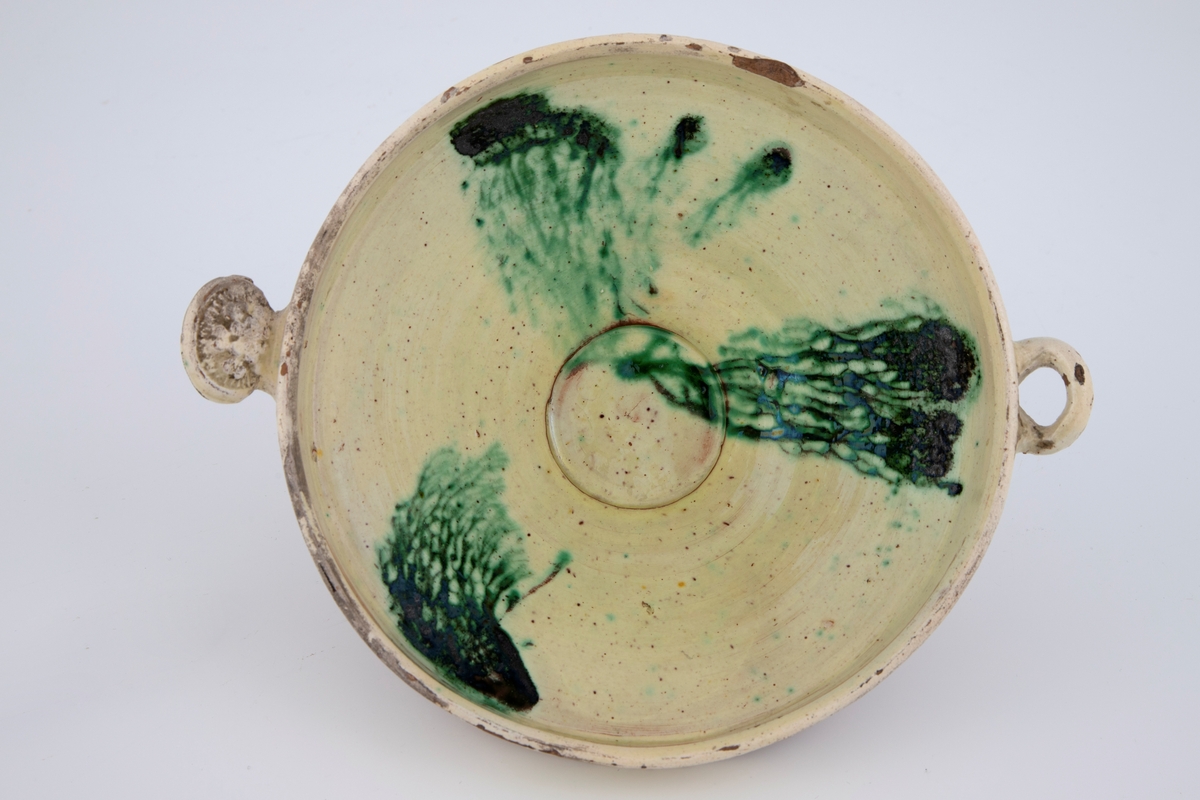 Tre punkter med rennede kobbergrønnglassur på skålens innside danner en abstrakt dekor.