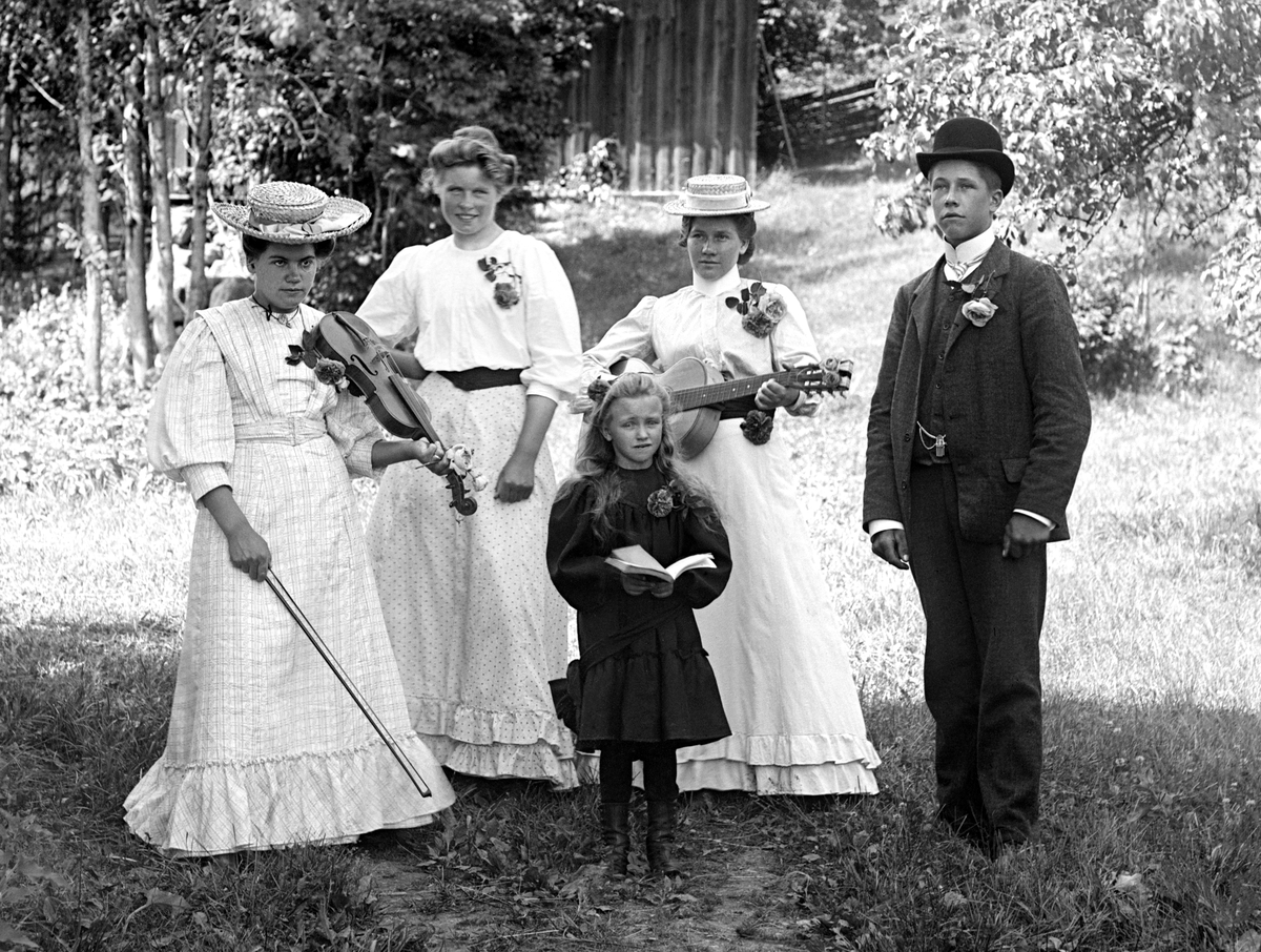 I trädgården hos fotograf Emil Durling har ett musikaliskt sällskap samlats. Stående näst längst till vänster är Ester Karlsson - mer känd som Ester Bölja Bergström efter ett taget tillnamn och giftermål. 

Anm: Identiteten av de övriga personerna har ej kunnat styrkas.