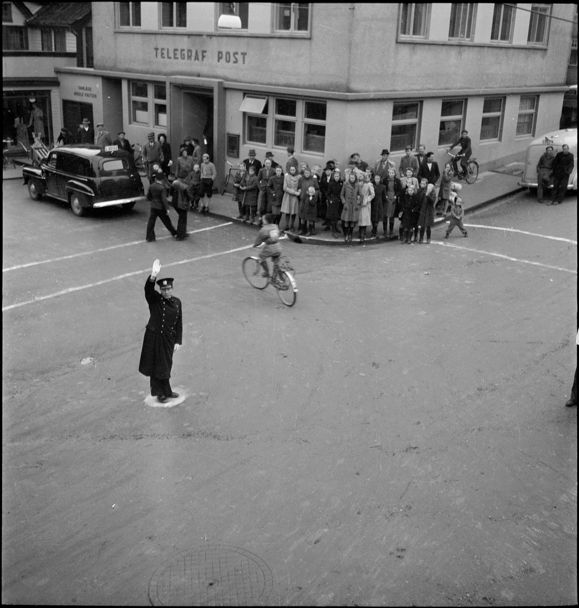 Trafikkuka i Egersund, 10.-16. november 1947. En konstabel dirigerer trafikken, og det arrangeres et sykkelrenn.
