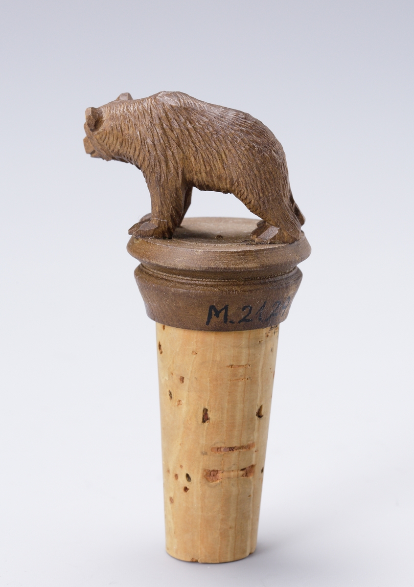 Flaskkork med överdel av snidad björn, på oval svarvad träsockel.

Inskrivet i huvudbok 1969.