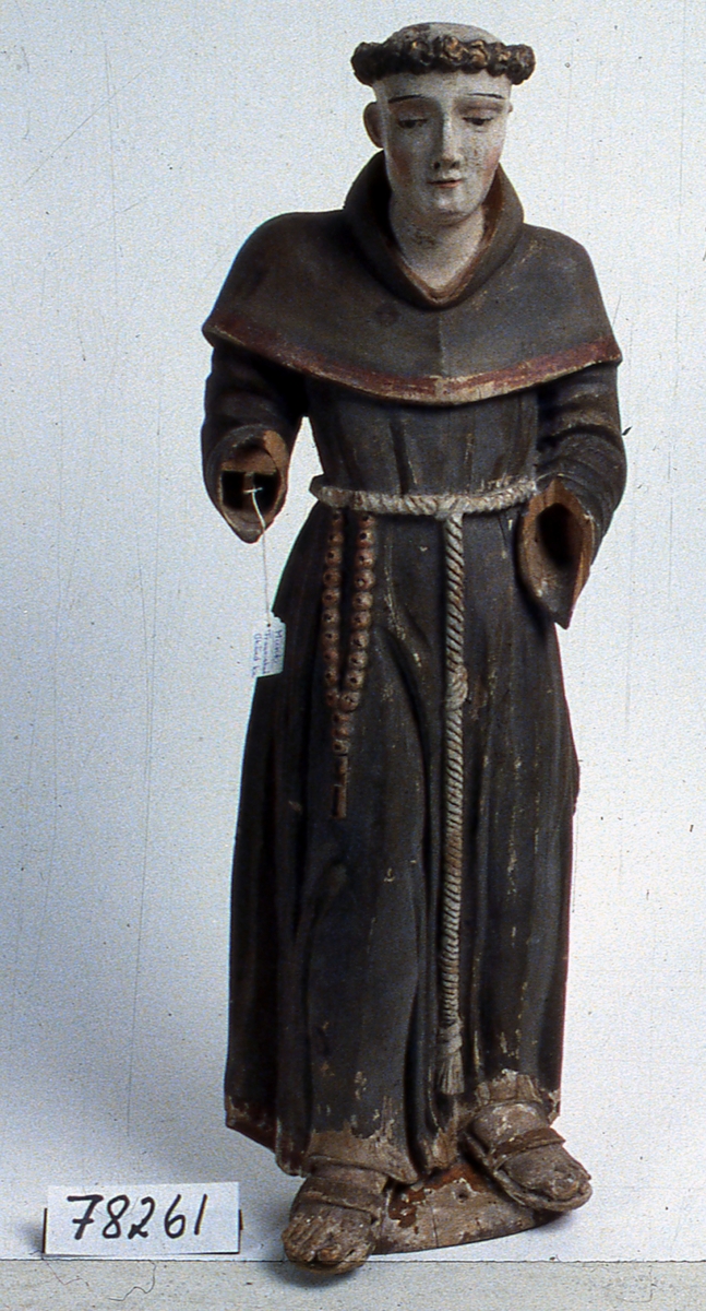 Skulptur av furu. Föreställer en munk, möjligen Franciskus, som står frontalt på en kupad fotplatta. Klädd i brun munkdräkt med rep om livet och sandaler på fötterna. En krans av bruna lockar omger huvudet, som har tonsur. Två plugghål i hjässan. Vänster öra avslaget. Händerna saknas. Det röda radbandet, som hänger vid repet i midjan, saknar det svarta korsets tvärarmar. Bit av repet ovanför radbandet saknas. Röd färg inuti hätta, på kapuschongkant och längst ned på dräkten. Färgen avflagad i nedre delen av dräkten och på fotplattan. På baksidan är hättans och kapuschongens konturer markerade.