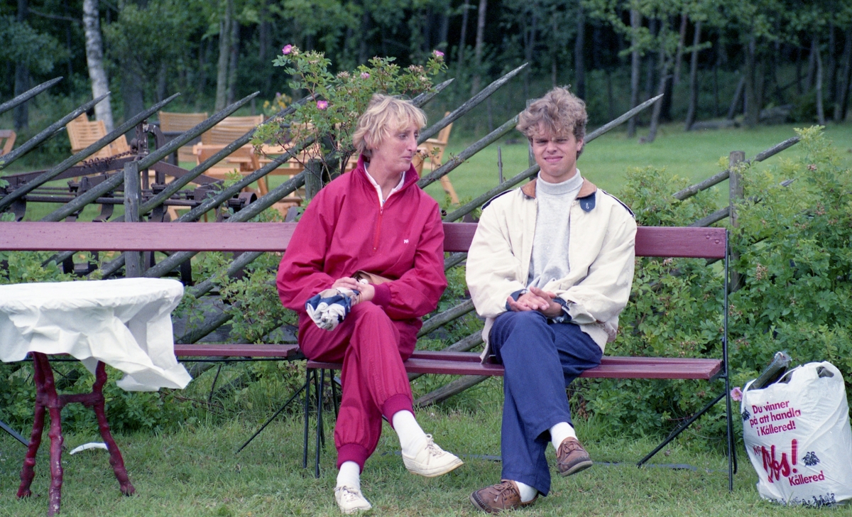 Troligtvis gökotta vid Hembygdsgården Långåker 1:3, 1980-tal. Eva Ivarsson och Robin Johansson sitter på en bänk utomhus. Till höger står en plastpåse från Obs! som senare blev Coop.