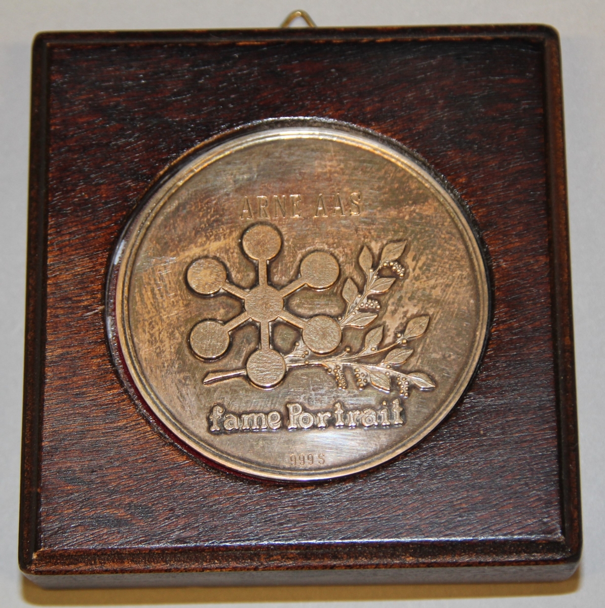 Sølvmedalje "Fame Portrait" Medlaja ligg i i ramme av tre, trekt med raud fløyel. Ramma er litt tjukkare i øvre kanten.
