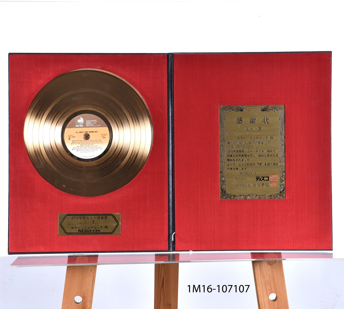 Guldskiva för All About ABBA/Mamma Mia, 1976. Utfärdat 1976. Japansk text. Guldskiva i läderomslag. Vänstra insidan sitter guldskiva fäst med en plakett under. Högra insidan en plakett. 

H 45 b36