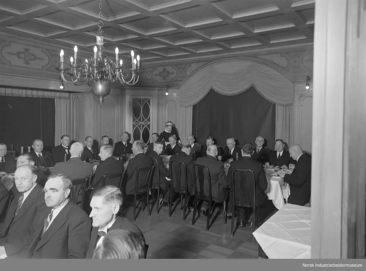 25.års jubilanter i Norsk Hydro 1939 og 1940. Middag på Administasjonsboligen. Serveringspersonale servere mat ved bordet.