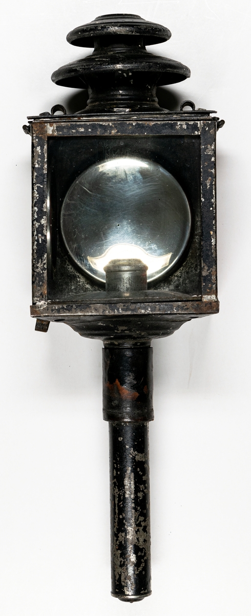 Kat.kort:
Vagnslykta, sidolykta till trossvagn, från Hälsinge regemente, omkr. 1900.
Av plåt, svart, rött glas, två metallspeglar inuti.