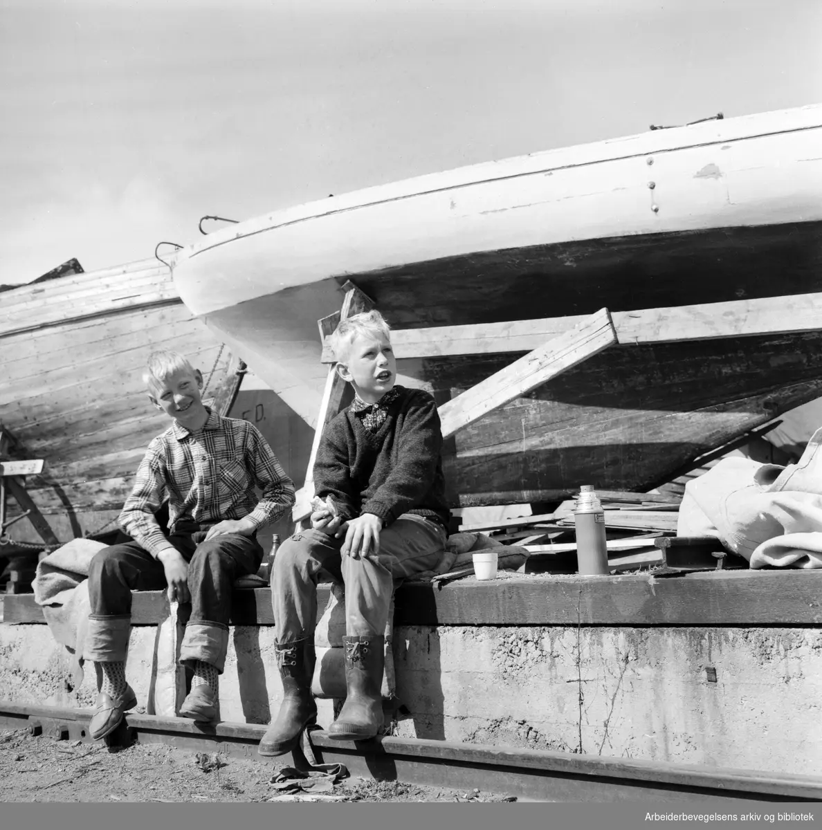 Trebåter i vinteropplag. Knut Erik Bockelie (til høyre) og klassekameraten Trond Bakkevig fra Nesbru i Asker pusser opp seilbåten Marmara. Karenslyst - Sjølyst. Mai 1960.