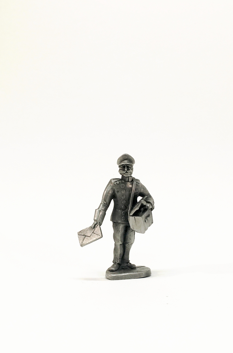 Figurin förställande en man i uniform med mössa och brevbärarväska. Han håller ett brev.
