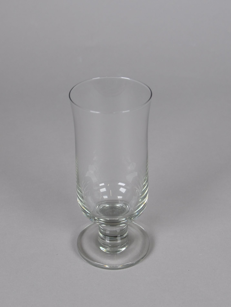 Grått hvitvinsglass. Glasset står på sylindrisk stett og rund sokkel. Glasset er sylindrisk, med svak konkav kurve under drikkeranden.
