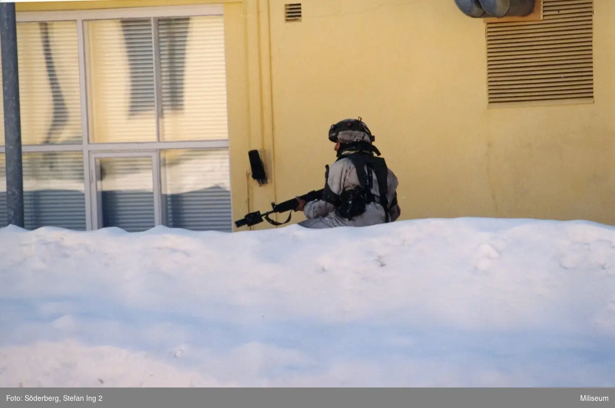 Kasernområde. Militärer bakom snövall.