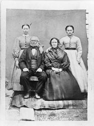 Trolig familieportrett av et eldre ektepar som sitter foran,
