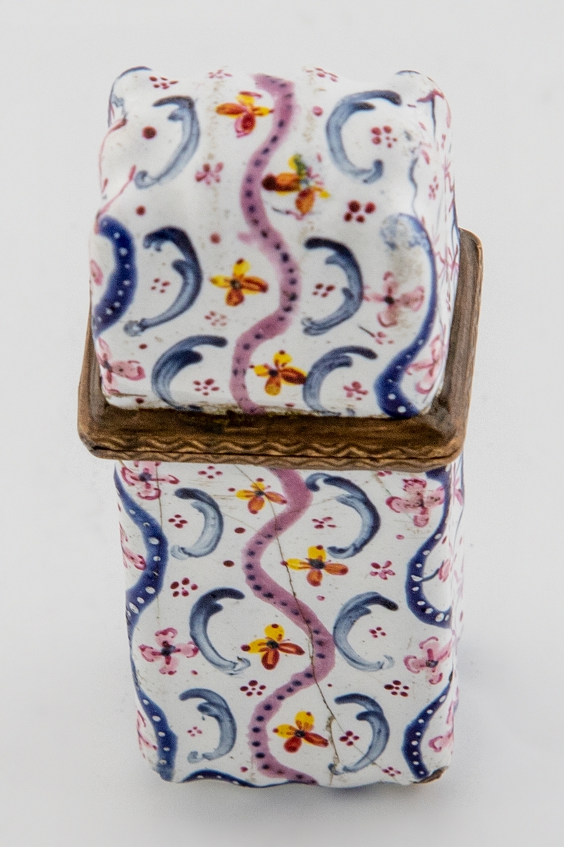 Rektangulært etui (svampehus) i emaljert kobber med hengslet lokk som er festet til kortsiden. Rokokkomønster i rødt, blått, gult og fiolett på hvit bunn på etuiets utside. Lokket er rosa på innsiden, mens etuiets korpus har hvit innside.