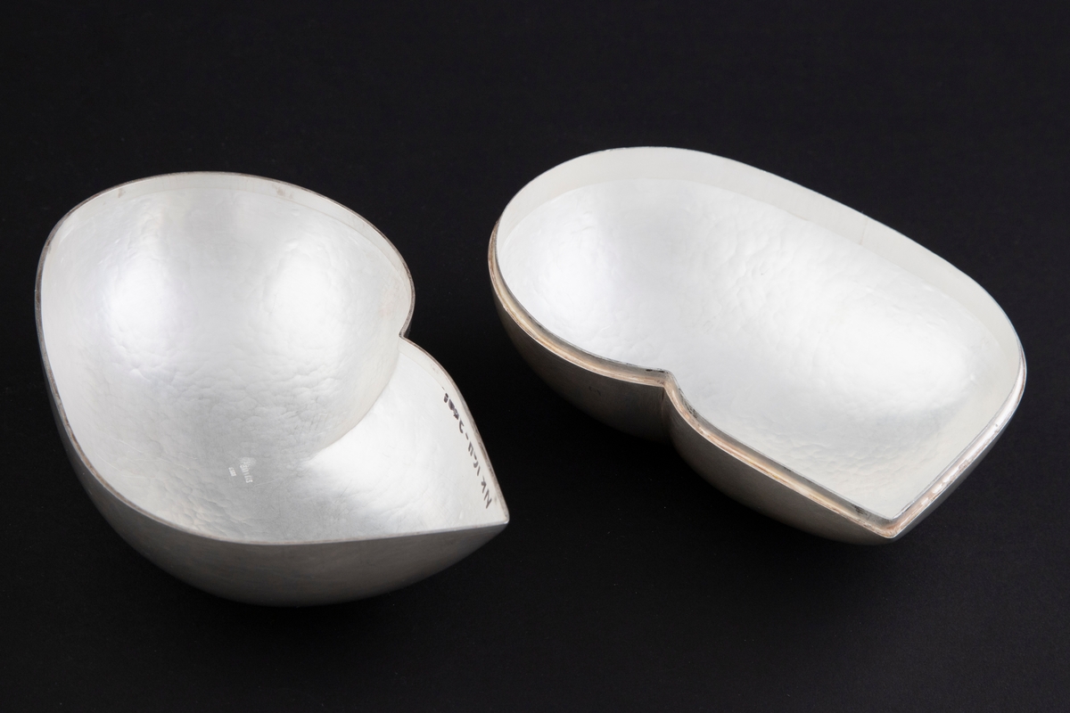 Bonnbonière i sølv. Oval, avrundet og voluminøs skulpturell form, som munner ut i en spiss på den ene siden. Lokkets og bunnens former speiler hverandre. Overflaten er matt, mens på innsiden har overflaten en hamret struktur.