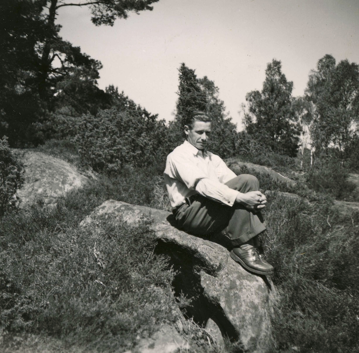 Rolf Svensson (1909 - 1989), iförd basker, sitter på en stenbumling vid Ekans gård, Ekan 1:1 år 1953. Han ägde och brukade gården.