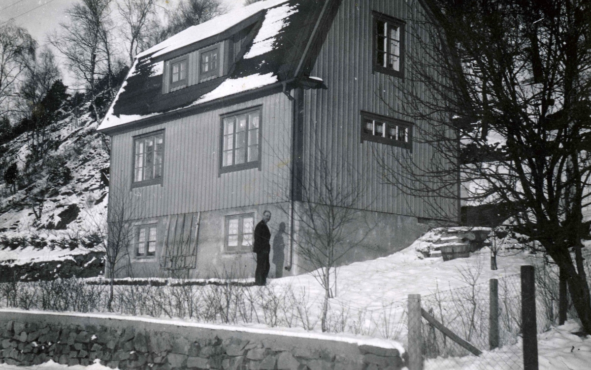 Husägaren Olof Olsson (1883 - 1958) står utanför "Alphyddan" Torrekulla 1:25, Gamla Riksvägen 13, okänd årtal. Det är vintertid och snö. Huset uppfördes 1933 av Olof och hustrun Sara.