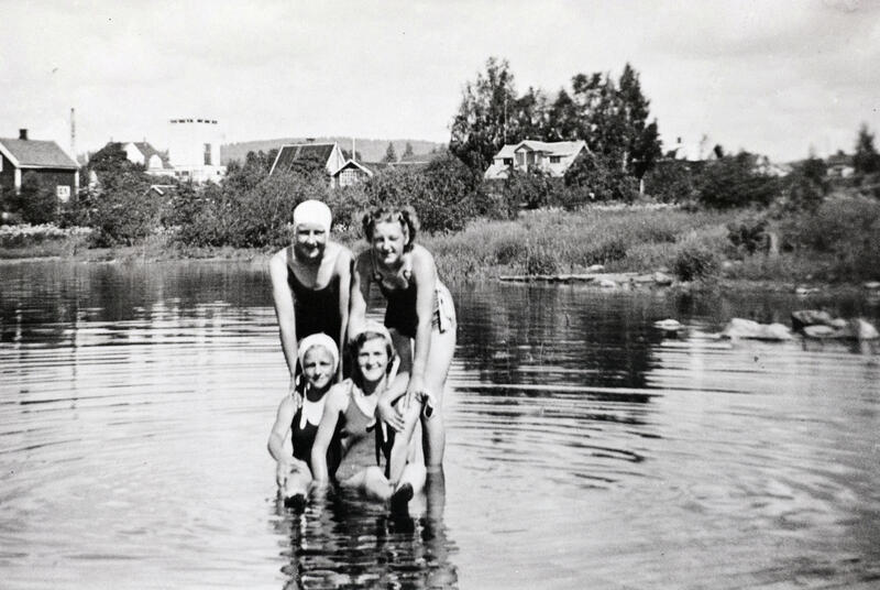 Svart-hvitt foto av fire unge damer med badedrakt og badehette ute i Mjøsa.