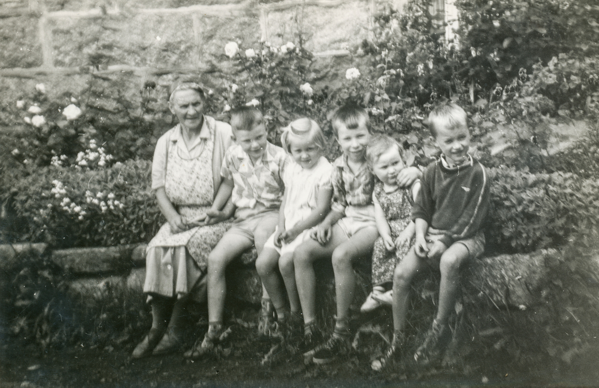 Bestemor med fem barnebarn i hagen ved gardshuset i Vasstun. 