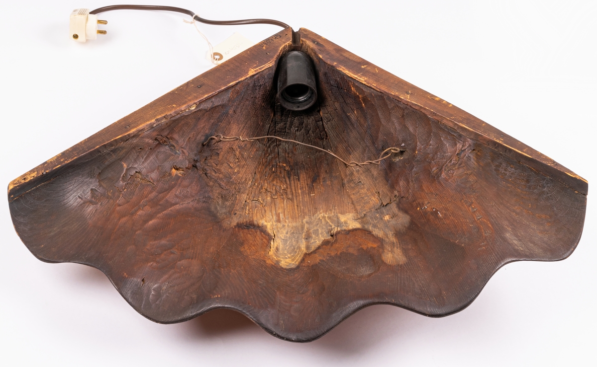 Vägglampa av furuträ skuren i ett stycke i form av mussla formgiven av konstnär Johnny Mattsson, Gävle.