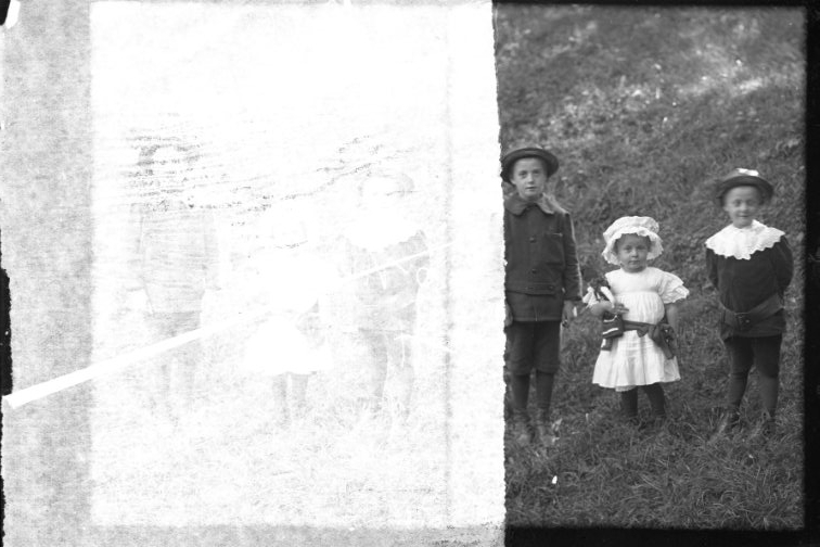 Porträtt av tre barn. Två pojkar på vardera sidan om en liten flicka. Två motiv på samma glasplåt.