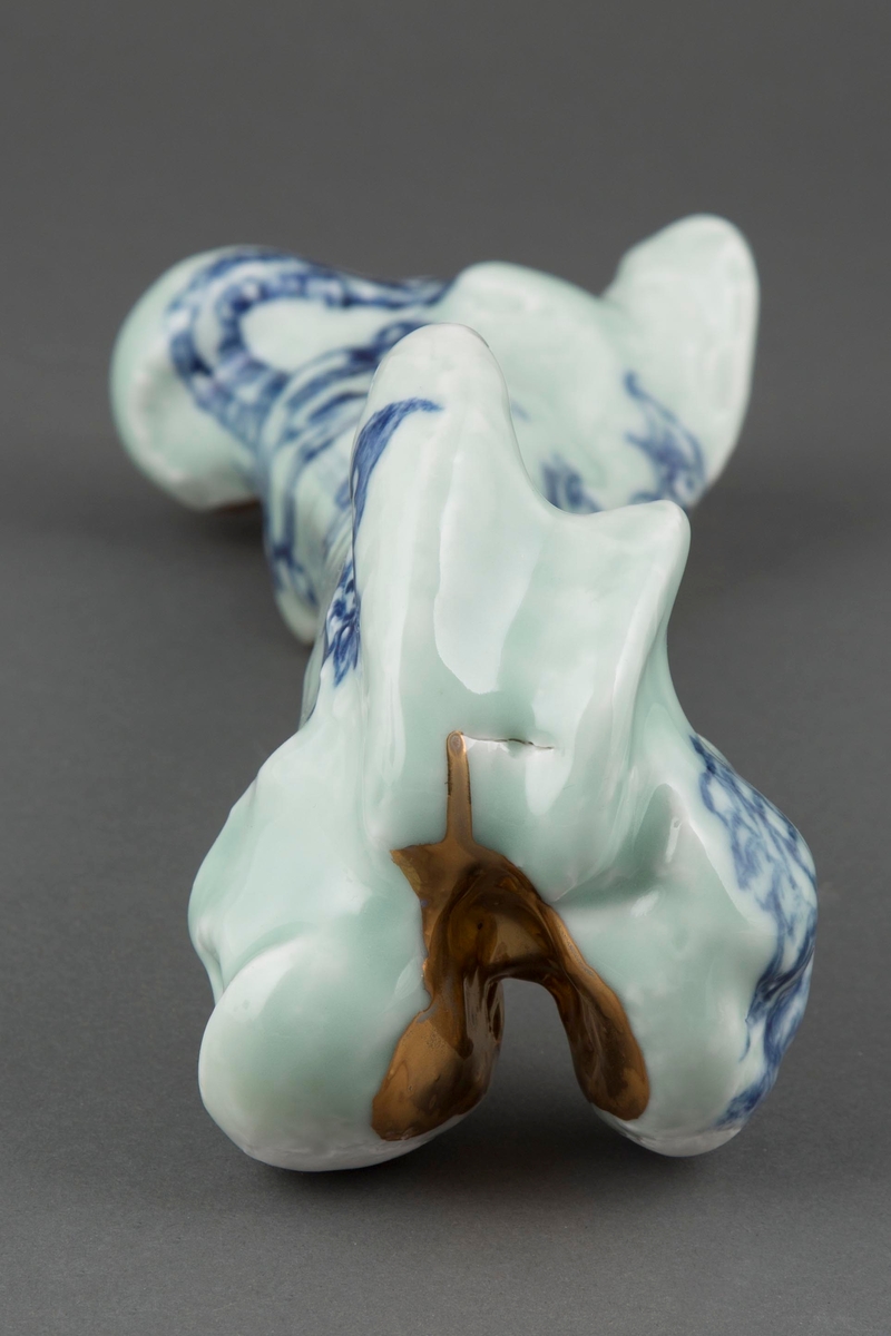 Et ben i porselen med sjømannstattoeringer i blå underglasur og bladgull.