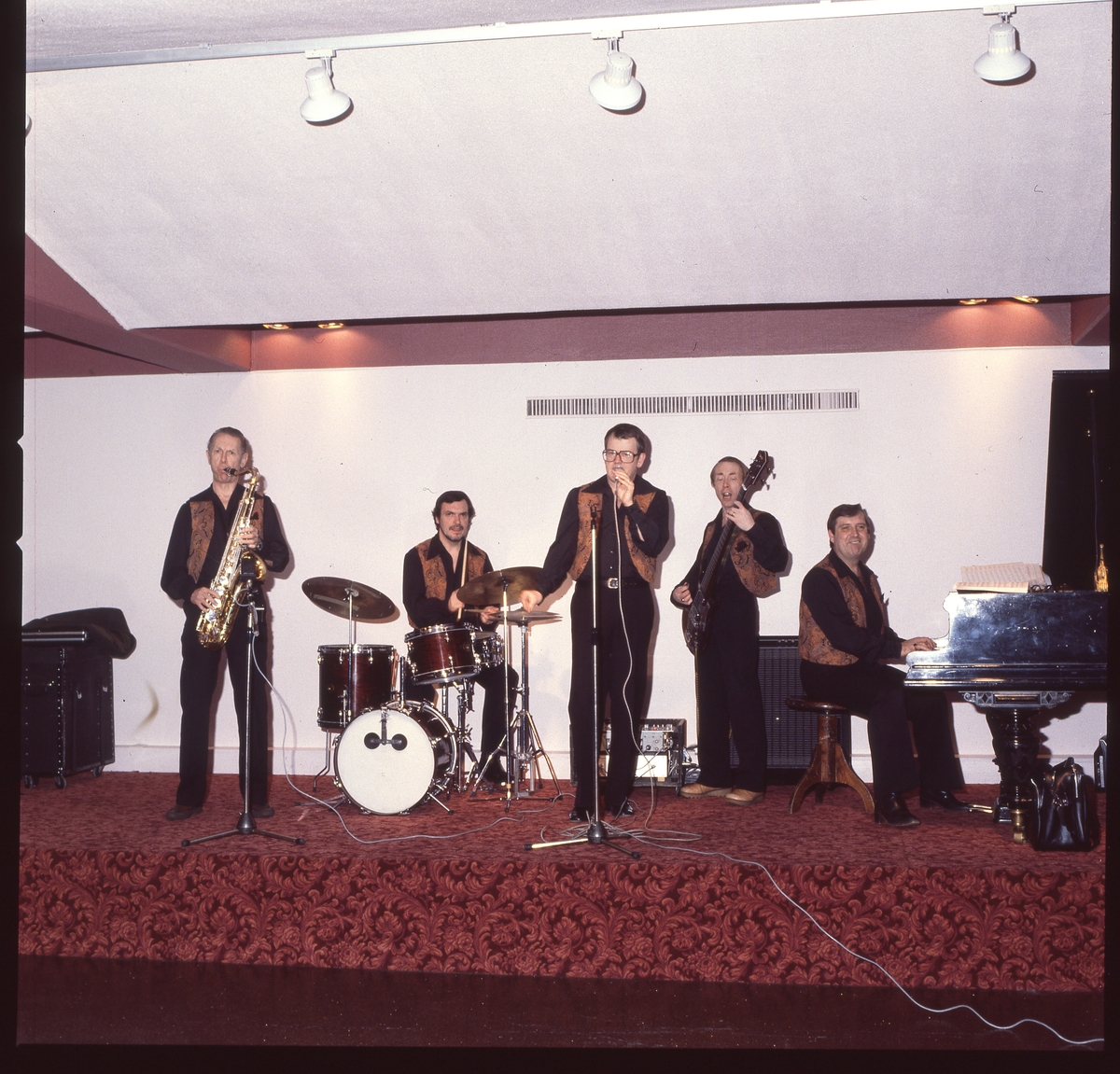 En positiv filmremsa på fyra bilder av ett dansband som spelar på en scen.