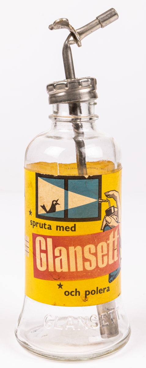 Glasflaska med pump av metall. Gul etikett men texten "Glansett". Har innehållit putsmedel till blanka ytor som glas och kakel.