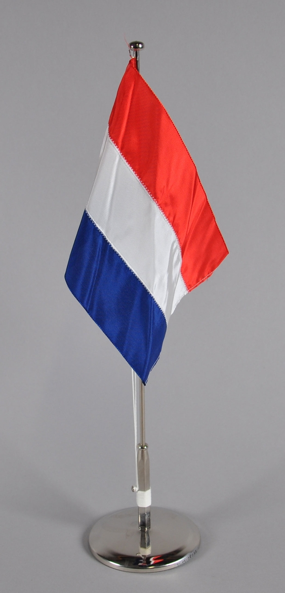Bordflagg fra Nederland. Tre horisontale striper, rødt øverst, hvitt i midten og blått nederst.