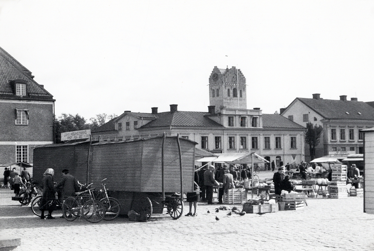 Växjö Stortorg, en torgdag på 1950-talet. Till vänster dåv. Post- och Riksbankshuset, följt av husen i kvarteret Lejonet vid Kronobergsgatan. Bakom dem syns domkyrkans torn.