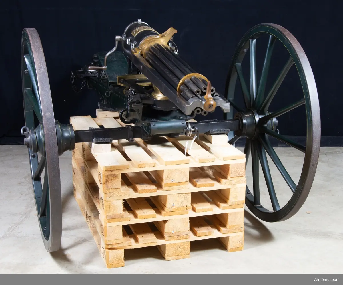 Grupp E IV a.
Tiopipig kulspruta, USA. Av amerikanske vapenfabrikanten Gatlings konstruktion patent 1865, med lavett samt där framför stående låda, fylld med patronmagasin.