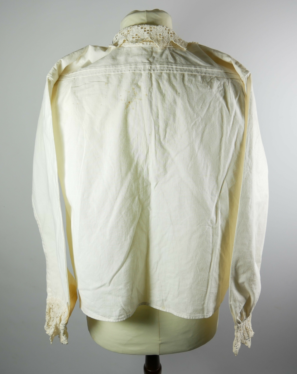 Hvit skjorte med krage, bryststykke og dekordetaljer på ermene i hardangersøm. 