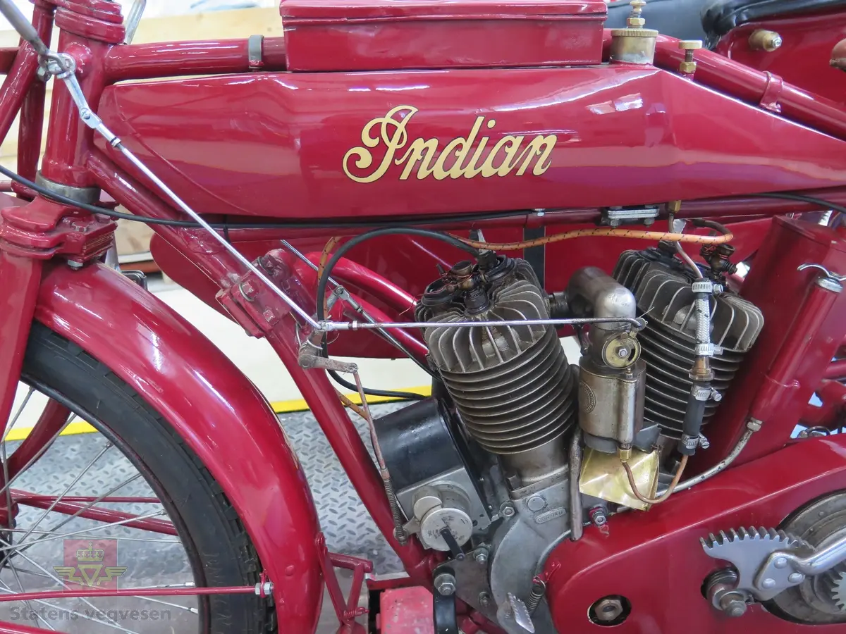 Indian Powerplus Model F. Motorsykkel med sidevogn, i hovedsak rød og svart. Brunt sete. Motoren er en 2-sylindret V-maskin av typen Power Plus. Det er en bensindrevet forbrenningsmotor med et volum på 997 ccm og en effekt på 15 hk (11,2 KW). To sitteplasser. Drift på bakre aksel. Dekkdimensjon foran og bak er 3X28.