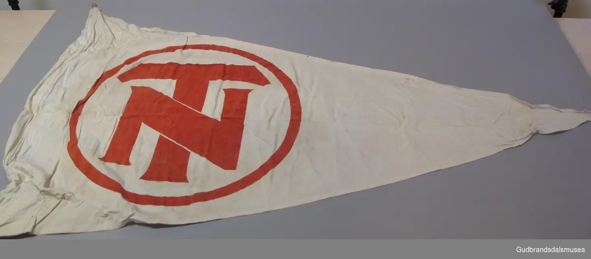 Vimpel med DNT-logo. Hvit bunn og rød DNT-logo. Brukt på Sandhaug turisthytte (DNT) rem til 1948.