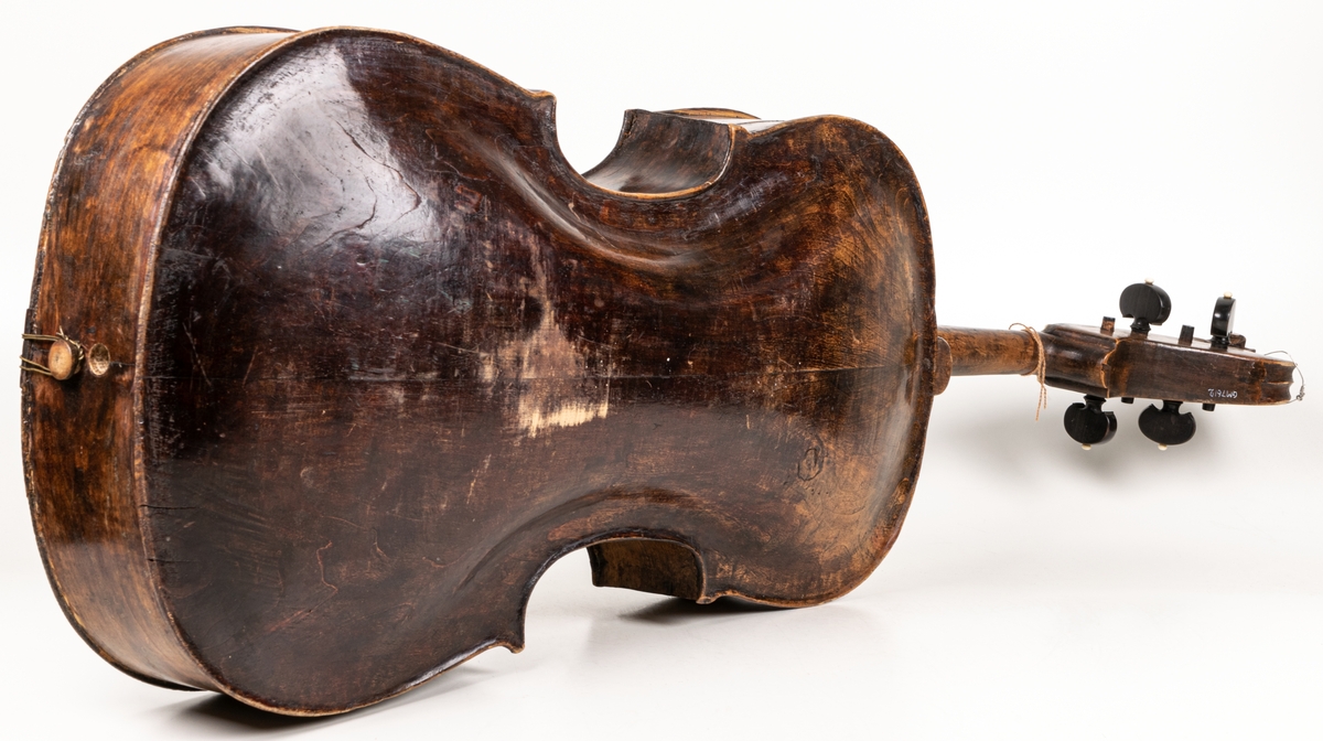 Cello, 1700-talet, brunsvart med 4 strängar, benknoppar på skruvarna för strängarnas spännande.