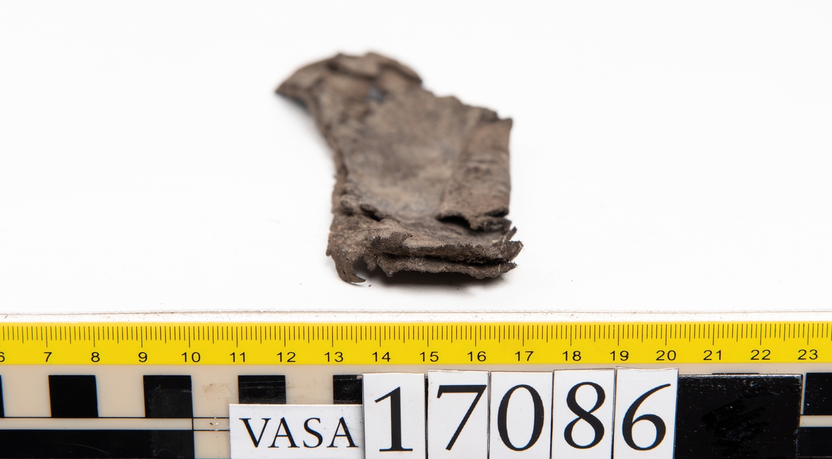 Ett 80-tal delar och fragment från skobotten samt möjligtvis delar från ovandel: sulor, holtrand mm.

På ett av fragmenten från holtranden finns kvarsittande skopligg.

Två hoprullade näverbitar som troligtvis utgjort delar av sulor eller inlägg.

En mindre bit fiberliknande material.

Lädret är mycket fragmentariskt och flertalet fragment är mycket små.