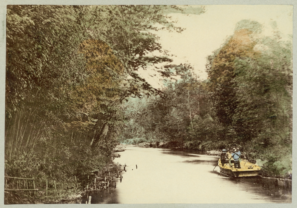 Biden föreställer en flod i skogen mellan Tokio och Nikko. Två män i en roddbåt trafikerar floden.
