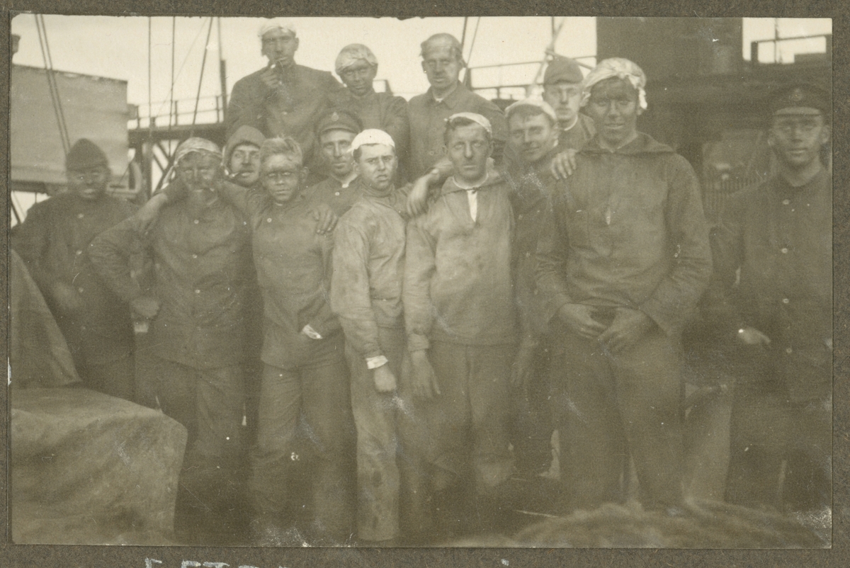 Bilden visar en grupp sjömän med smutsiga ansikten och arbetskläder på däck av Fylgia.
