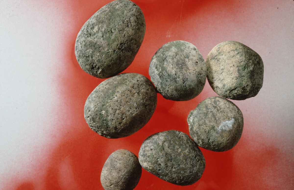 Sju knakkesteiner av granittisk bergart med knusespor. St. m. 75-40 mm.