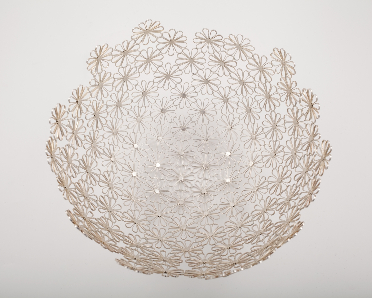 Halvkuleformet bolle i sølvfiligran, som danner et nettverk bestående av stiliserte blomsterformer.