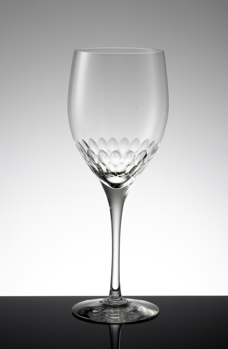 Design: Nils Landberg.
Ölglas. Tulpanformad kupa med fjällslipning på nedre delen. Högt, draget ben. 
Fabriksmärke: mörkgrå botten med vit text.