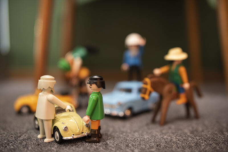 Playmobilfigurer og lekebiler på gulv, fra utstillingen Små biler - store gleder.